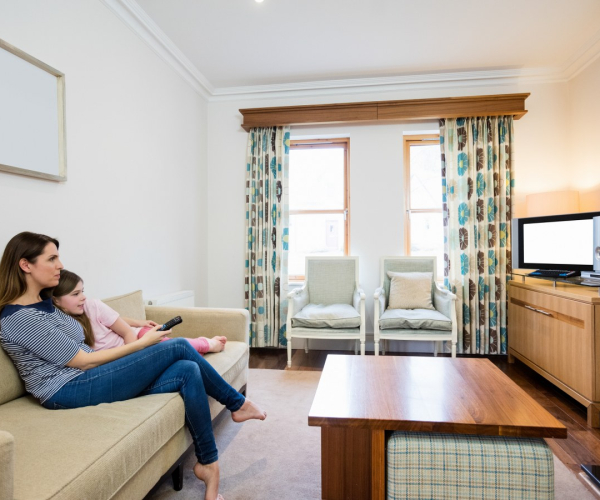 Mother and daughter watching tv in living room at home